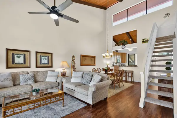 Living area featuring comfortable seating, high ceilings, and stairs to loft