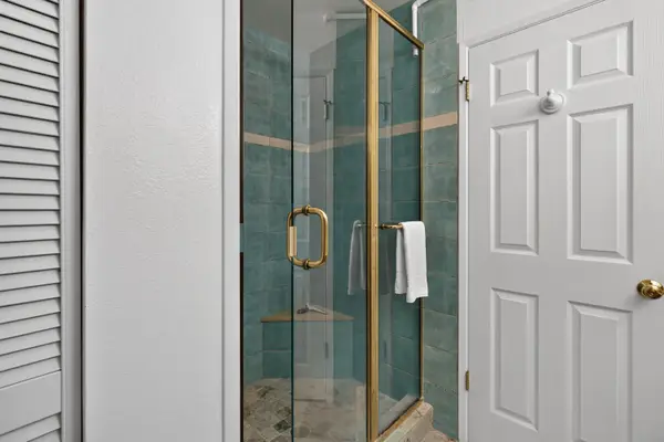 Walk-in glass shower enclosure with blue-green tile wall