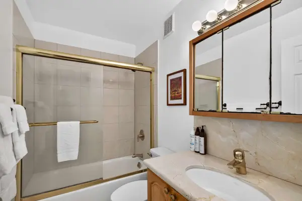 En-suite bathroom featuring bathtub with sliding glass doors and vanity mirror