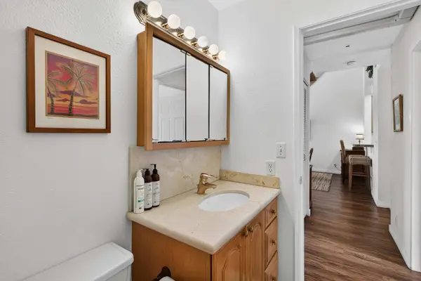 Primary bathroom vanity with mirrored cabinet and doorway leading to bedroom