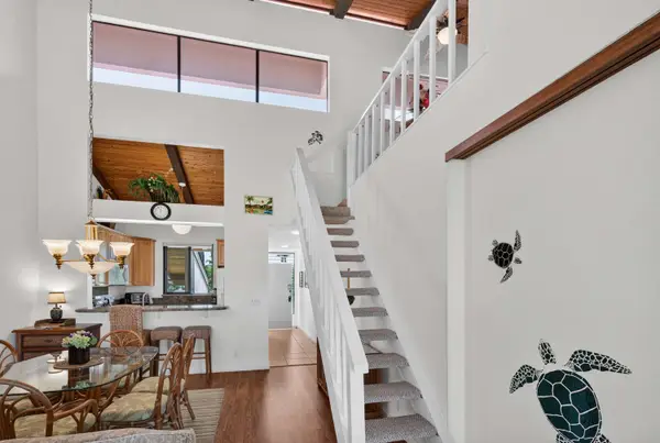 Open living area with high ceilings, dining table, and staircase leading to loft