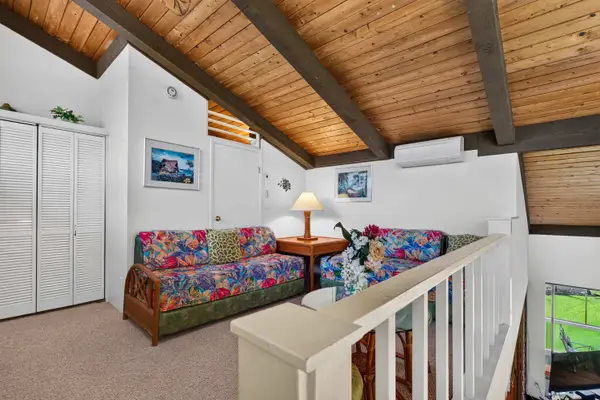 Upstairs loft featuring twin beds, vaulted wood ceilings, and closet space