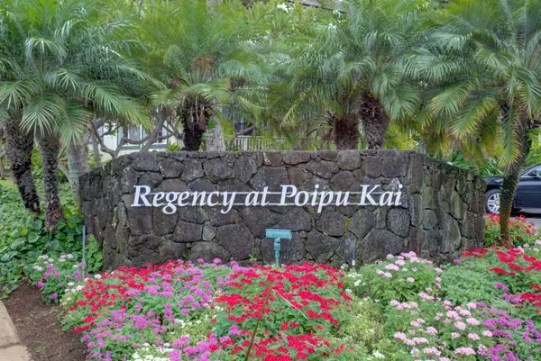 Community Entrance Sign Surrounded by Palms and Blooming Flowers