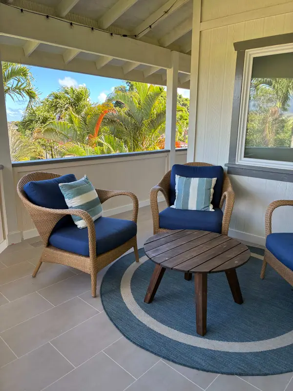 Covered outdoor lounge nook featuring woven chairs & Accent table