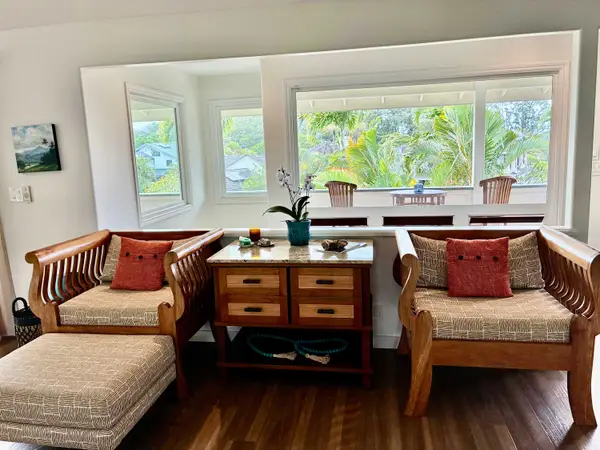 Sunlit living room seating area with natural wood chairs and poufs