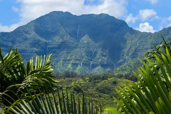 Mountain-view balcony offers comfortable seating beside lush greenery and hills
