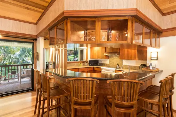 Wooden kitchen presents island seating, cabinetry, and practical appliances throughout