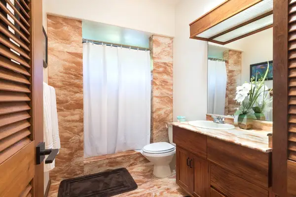 Bathroom vanity area features wood cabinetry, mirror, and fresh tilework