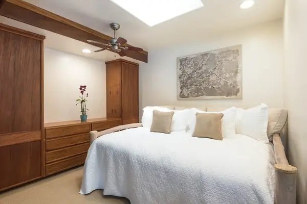Spacious bedroom combines comfortable bedding, wood accents, and tropical windows