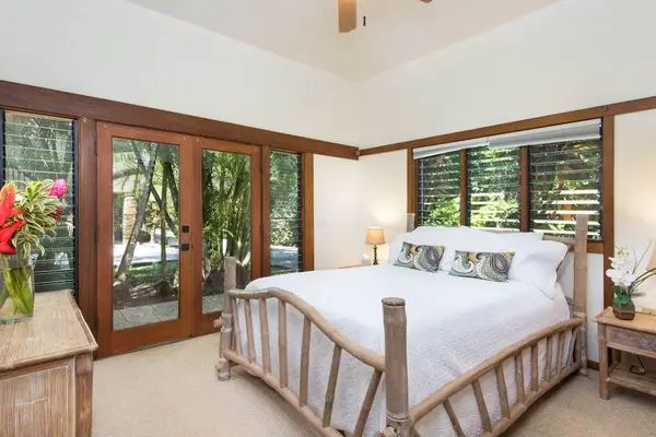 Garden-view bedroom showcases cozy bedding, wood details, and bright windows