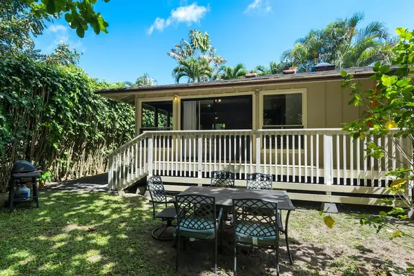 Raised home exterior showcases a deck, stairs, and lush landscaping
