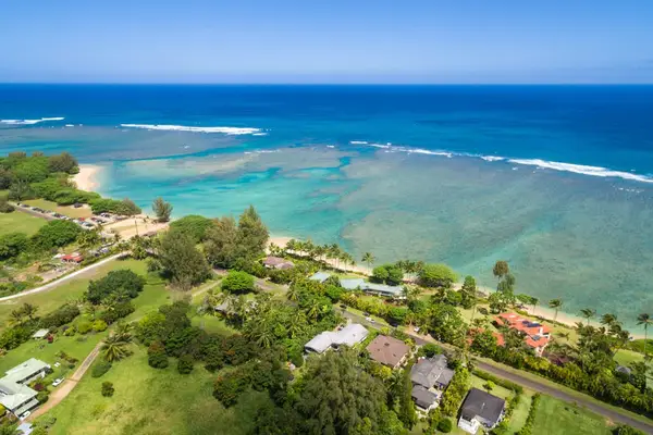Aerial coastline view showcases turquoise water, green hills, and sandy beaches