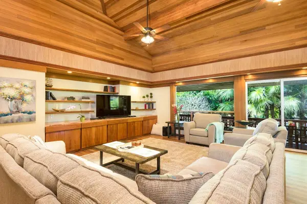 Open living room showcases wood ceilings, comfortable seating, and kitchen access