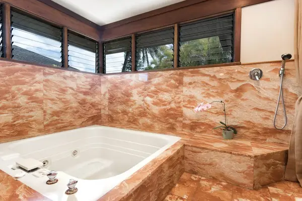 Marble bathroom highlights a soaking tub, windows, and stone surroundings