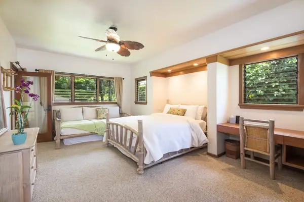 Bright bedroom offers comfortable bedding, practical furnishings, and garden views