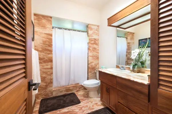 Contemporary bathroom showcases a shower, vanity, and warm tilework