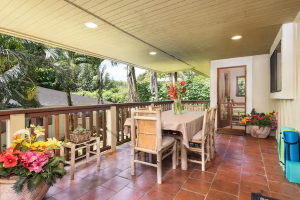 Covered dining patio provides colorful seating beside tropical garden surroundings