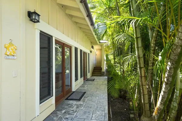Side exterior walkway passes beneath lush foliage beside the residence