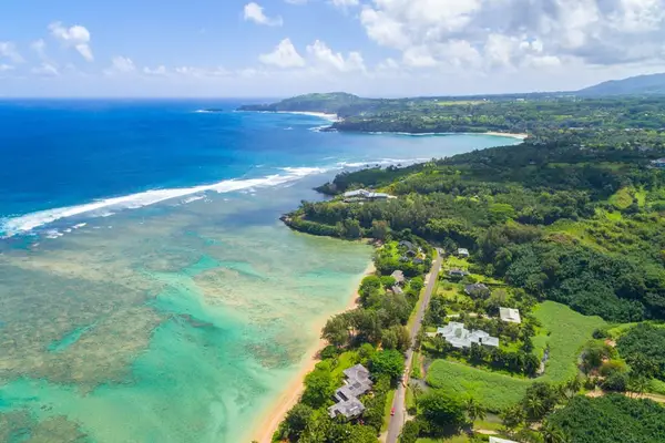 Aerial coastline view showcases turquoise water, hills, and sandy beaches