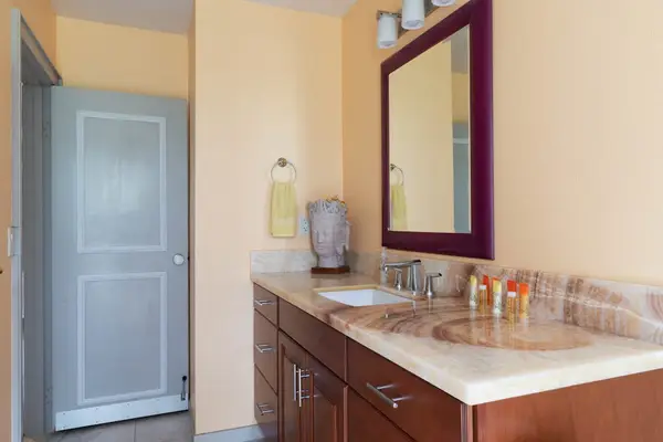 Clean Guest Bathroom Featuring Large Vanity Mirror & Long Countertop