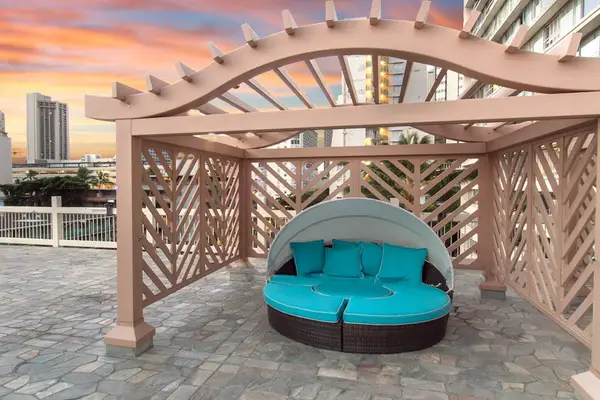 This comfortable outdoor cabana offers a private nook under a shade trellis for relaxing.