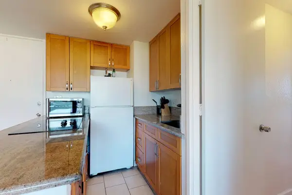 Prepare your favorite meals in the kitchen space, equipped with smooth granite countertops, traditional wooden cabinetry, and a full-size refrigerator.
