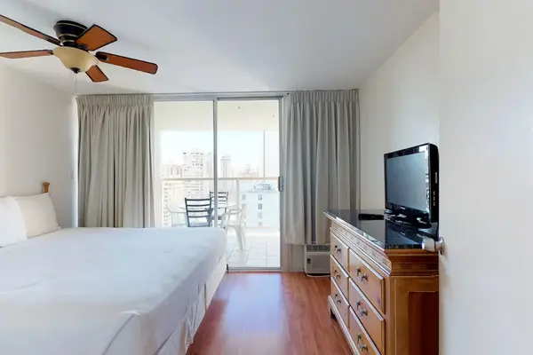 Wake up to natural light and stunning elevated views in this private bedroom, complete with a flat-screen TV, a classic wooden dresser, and direct sliding glass door access to the outdoor balcony.