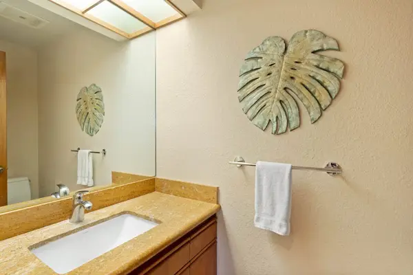Bathroom vanity showcases mirror, counter space, lighting, tilework, and storage