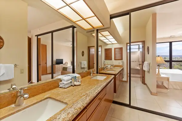 Ensuite bathroom includes dual vanities, mirrors, lighting, tilework, and fixtures