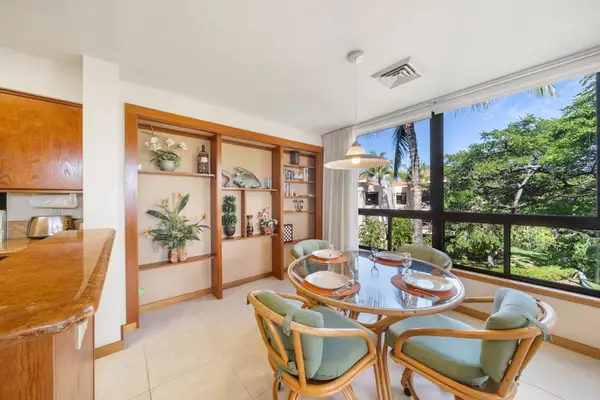 Dining area pairs table, colorful chairs, artwork, and garden views