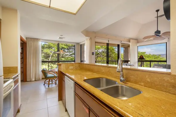 Kitchen workspace includes island counters, appliances, stools, windows, and artwork