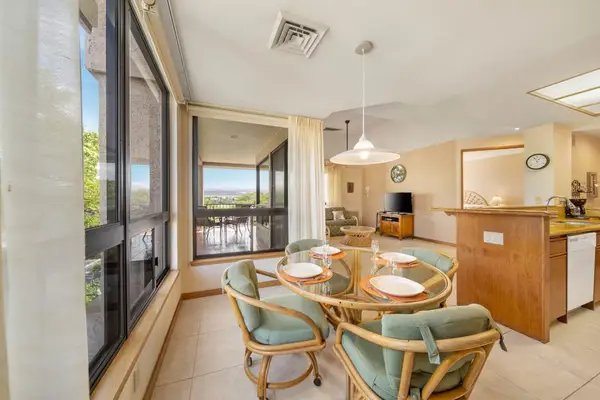 Dining setting pairs table, chairs, kitchen access, artwork, and windows