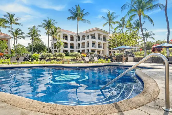 Resort pool glows beside palms, balconies, loungers, and tropical landscaping