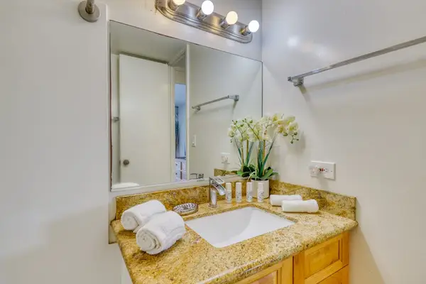 Clean, modern bathroom with a granite vanity, fresh towels, and complimentary essentials.