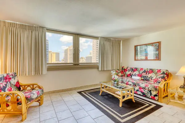 Bright and spacious living room with large windows showcasing beautiful Waikiki city views and plenty of natural light.
