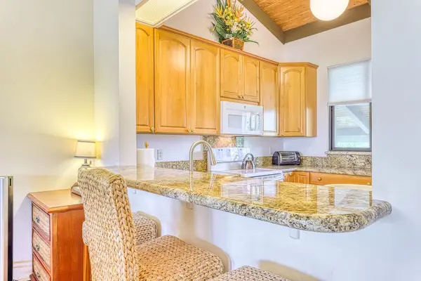 Fully equipped kitchen featuring warm wood cabinetry, granite countertops, and all the essentials you need to whip up delicious vacation meals! 🍳🥘🍍