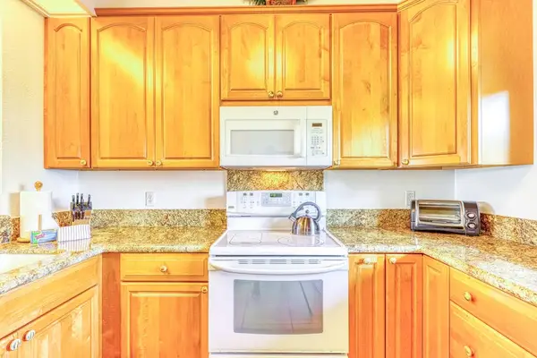 Fully equipped kitchen featuring warm wood cabinetry, granite countertops, and all the essentials you need to whip up delicious vacation meals! 🍳🥘🍍