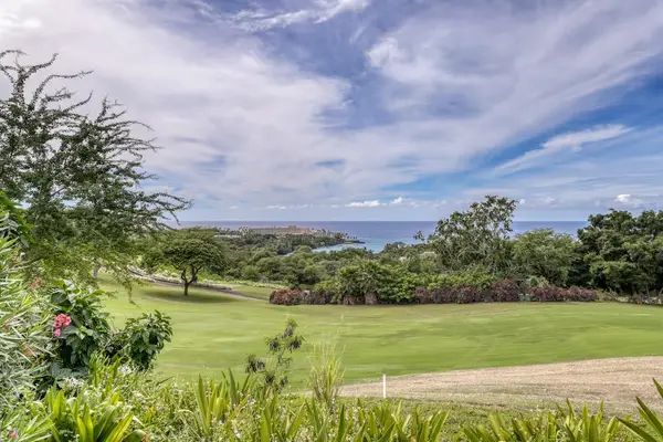 A serene, postcard-worthy view of rolling green lawns stretching toward the sea