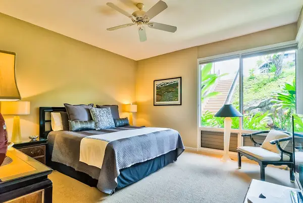 Master bedroom with king bed, flat screen tv and large windows for tropical views and private lanai access.