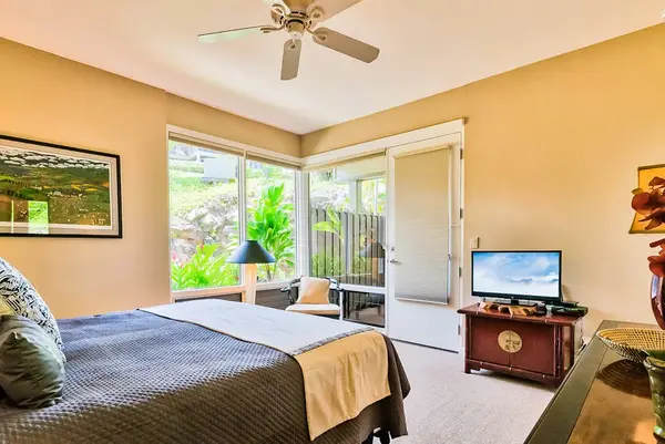 Master bedroom with king bed, flat screen tv and large windows for tropical views and private lanai access.