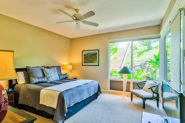 Master bedroom with king bed and large windows for tropical views and private lanai access.