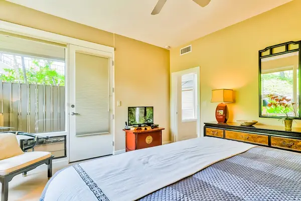 Master bedroom with king bed, flat screen tv and large windows for tropical views and private lanai access.