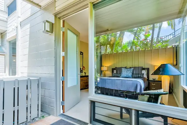 Master bedroom with king bed and large windows for tropical views and private lanai access.