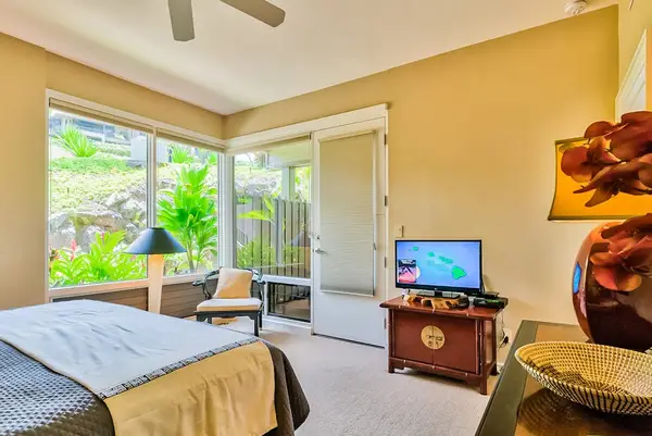 Master bedroom with king bed, flat screen tv and large windows for tropical views and private lanai access.