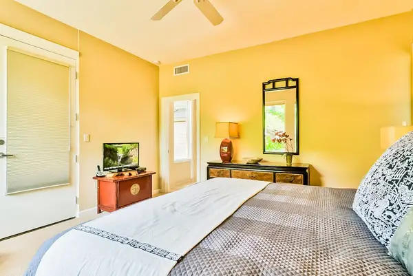 Master bedroom with king bed, flat screen tv and large windows for tropical views and private lanai access.