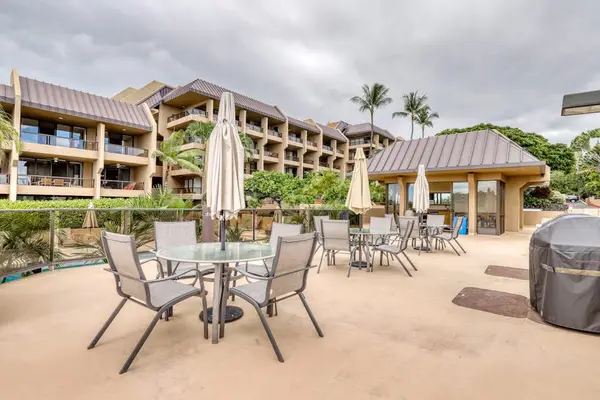 Shared resort patio deck featuring outdoor dining tables, shade umbrellas, spacious guest seating, and beautiful property views! ☀️🌴