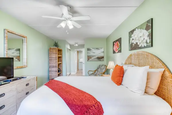 Fully furnished bedroom featuring a cozy bed setup, overhead ceiling fan, spacious storage dresser, and a large vanity wall mirror! 🛏️✨
