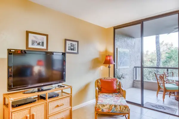Spacious living room media center featuring a flat-screen TV, console storage, cozy armchair, and large glass balcony sliding doors! 📺🛋️