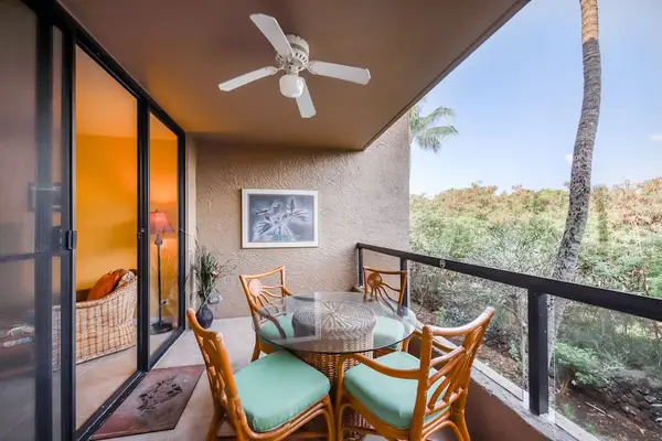 Shaded balcony setup featuring outdoor dining table, cushioned chairs, ceiling fan, and beautiful tropical treetop views! 🎛️📐