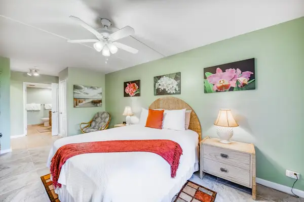 Upgraded bedroom layout featuring an overhead ceiling fan, styled bed, matching storage furniture, and chic accent wall decor! 🛏️🌀
